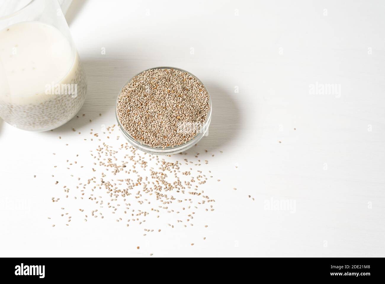Eingetaucht in ein Glas weißer Chia-Samen auf hellem Hintergrund, trocken Chia in einer Glasplatte, vegetarische gesunde Lebensmittel mit Omega und Vitaminen. Superfood fo Stockfoto