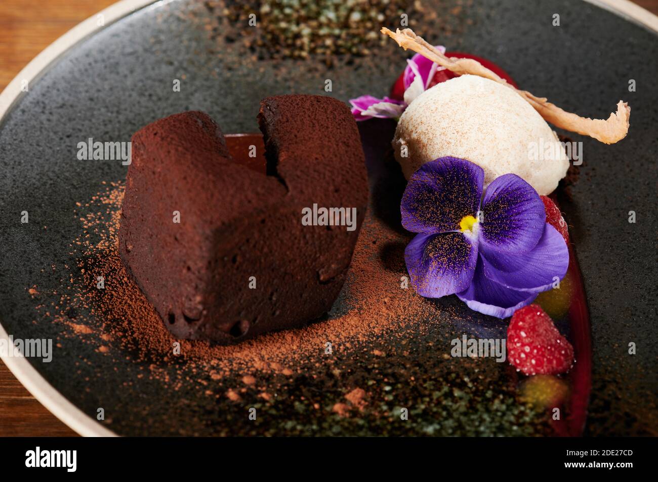 Eis mit Brownie und Blumen Gourmet auf schwarzem Teller Stockfoto