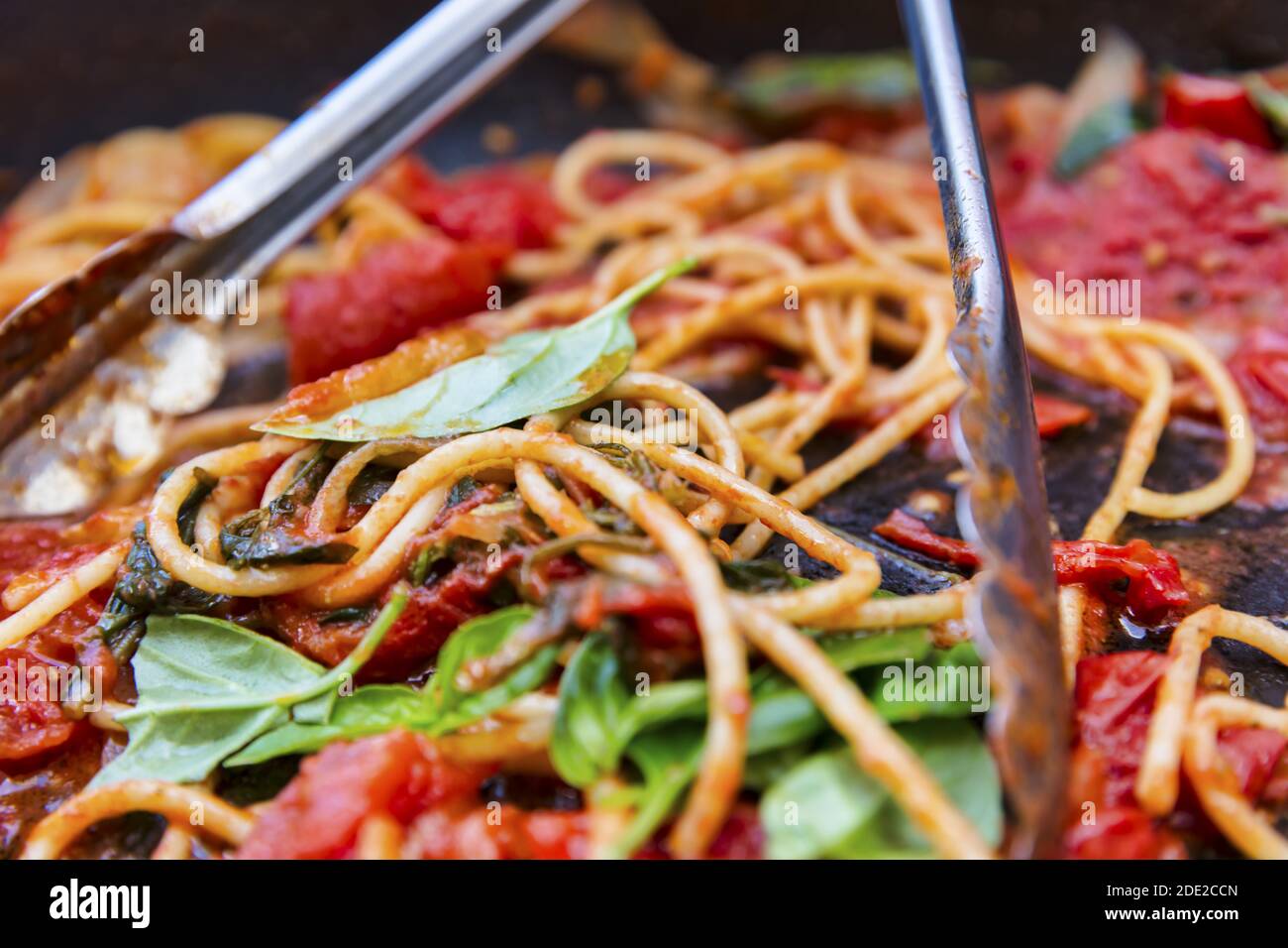 Eine rustikale zubereitete Mahlzeit aus frisch gekochten Spaghetti, würzigen Tomaten und duftendem grünem Basilikum. Schnell vorbereitet, um mit der Familie und Freunden zu teilen. Stockfoto