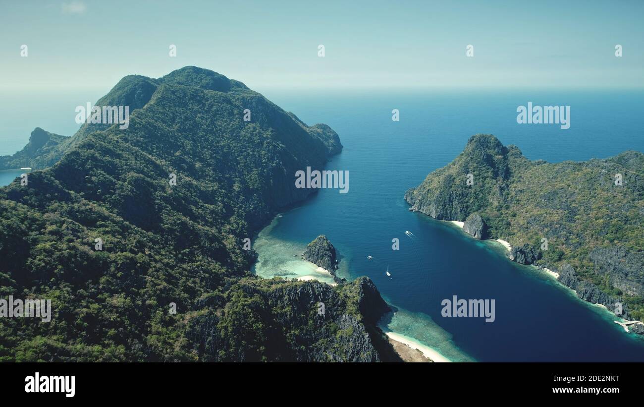 Bergige grüne Inselchen an der Meeresbucht Küste Luftaufnahme. Erstaunliche Seestape von grünen tropischen Wald auf hügeligen Inseln von El Nido, Philippinen. Naturlandschaft des blauen Ozeans Wasser im Sommer sonnigen Tag Stockfoto