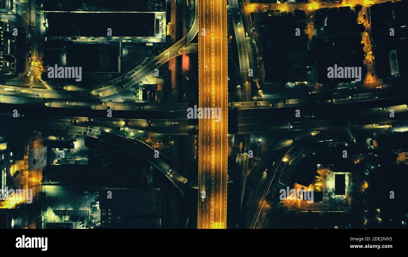 Top down Nacht Stadtverkehr Autobahn an Laternen mit Beleuchtung Stadtbild Luftbild. Downtown Outdoor-Landschaft mit moderner Architektur von Wolkenkratzern Gebäude. Filmische Stadt Philippinen Stockfoto