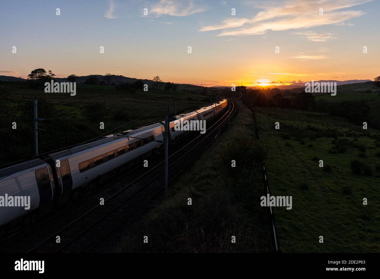 Avanti West Coast Alstom Pendolino Zug kippen 390117 auf ein Kurve in Richtung Sonnenuntergang an der Hauptlinie der Westküste In der Cumbrian Landschaft Stockfoto