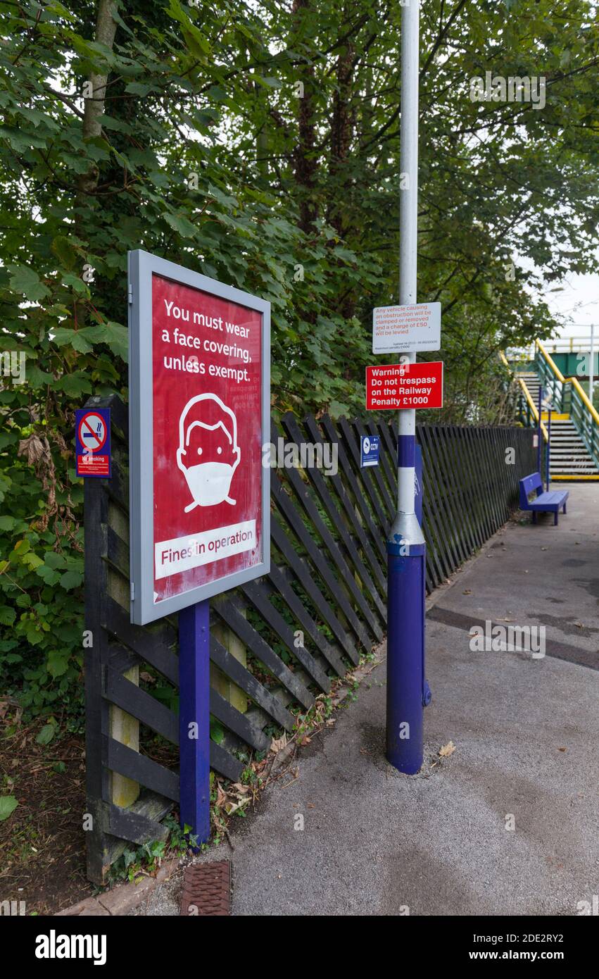 Schild an einem britischen Bahnhof, der Bahnreisende anweist, während der 2020 Coronavirus/covid 19 Pandemie eine Gesichtsbedeckung/Gesichtsmaske zu tragen Stockfoto
