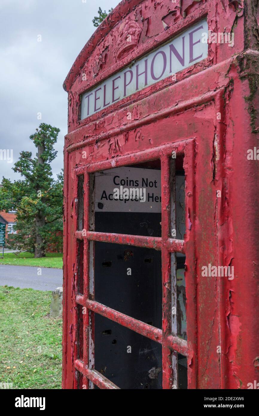 Verlassene alte rote Telefonbox mit zerbrochenem Glas und Rote Farbe blättert ab Stockfoto