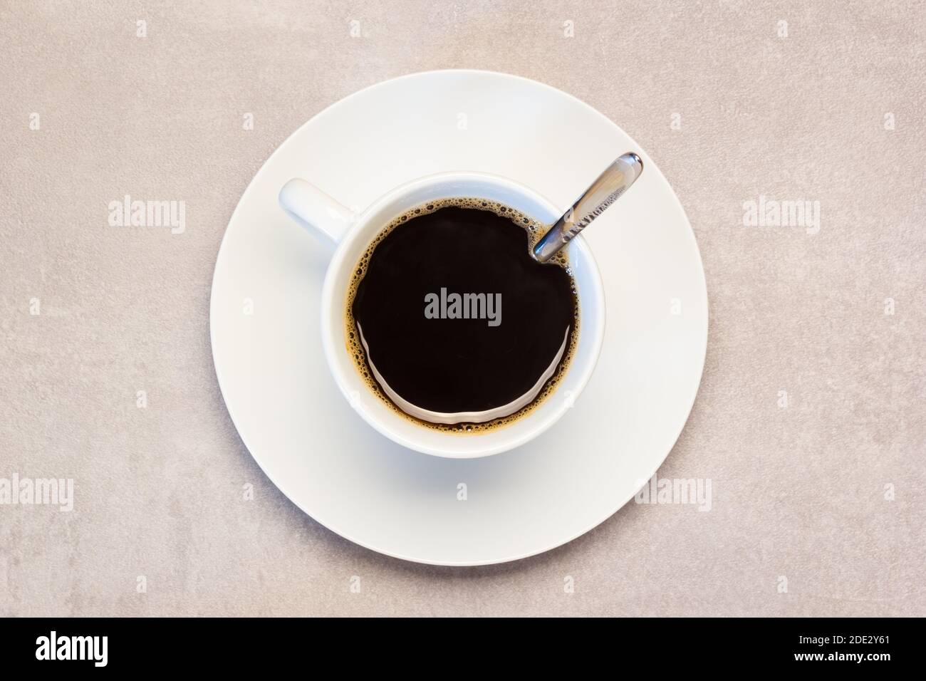 Eine gefüllte Tasse mit frisch gebrühtem Kaffee und Löffel auf Arbeitsplatte Stockfoto