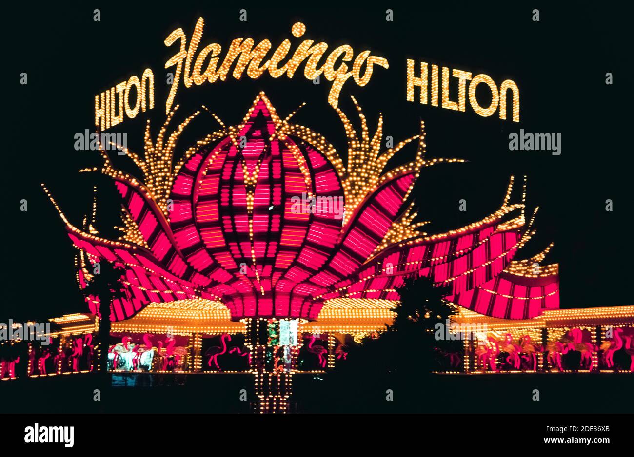 Neon und andere bunte Lichter machten dieses Outdoor-Schild für das Flamingo Hotel & Casino bei Nacht am Las Vegas Boulevard, besser bekannt als der Strip, eine Straße mit spektakulären Resort-Hotels und Casinos südlich der Stadtgrenze von Las Vegas, Nevada, USA. Das Flamingo wurde 1946 eröffnet, eine sehr frühe Attraktion in diesem berüchtigten Wüstenziel, das für sein Glücksspiel und seine guten Zeiten bekannt ist. Das Hotel gehörte der Hilton Corp., als dieses historische Foto im Jahr 1983 aufgenommen wurde. Ein Jahrzehnt später wurde das ursprüngliche Hotel abgerissen, aber dieses einzigartige Zeichen von stilisierten rosa Federn wurde gerettet. Stockfoto