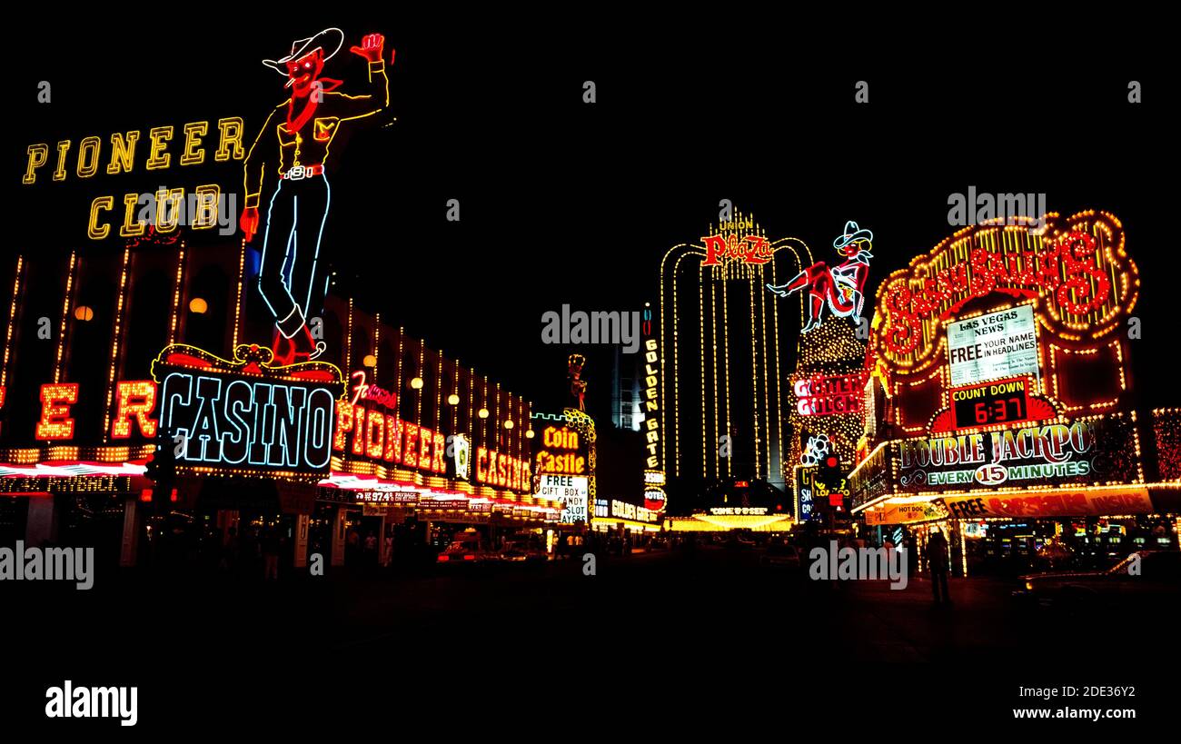 Neon und andere bunte Lichter machten diese Outdoor-Schilder für Casinos und Hotels in der Nacht und während des Tages an der Fremont Street, dem ursprünglichen Stadtzentrum für Glücksspiel und gute Zeiten in Las Vegas, Nevada, USA, hervorstechen. Leicht zu erkennen in der Neon-Anzeige sind ein Cowboy und ein Cowgirl mit dem Spitznamen Vegas Vic und Vegas Vickie. Seit der Aufnahme dieses historischen Fotos im Jahr 1983 wurde die Fremont Street mit einem Baldachin bedeckt, das die längste Videowand der Welt ist und Besuchern in der Fußgängerzone eine Sound-and-Light-Show über dem Kopf präsentiert. Stockfoto