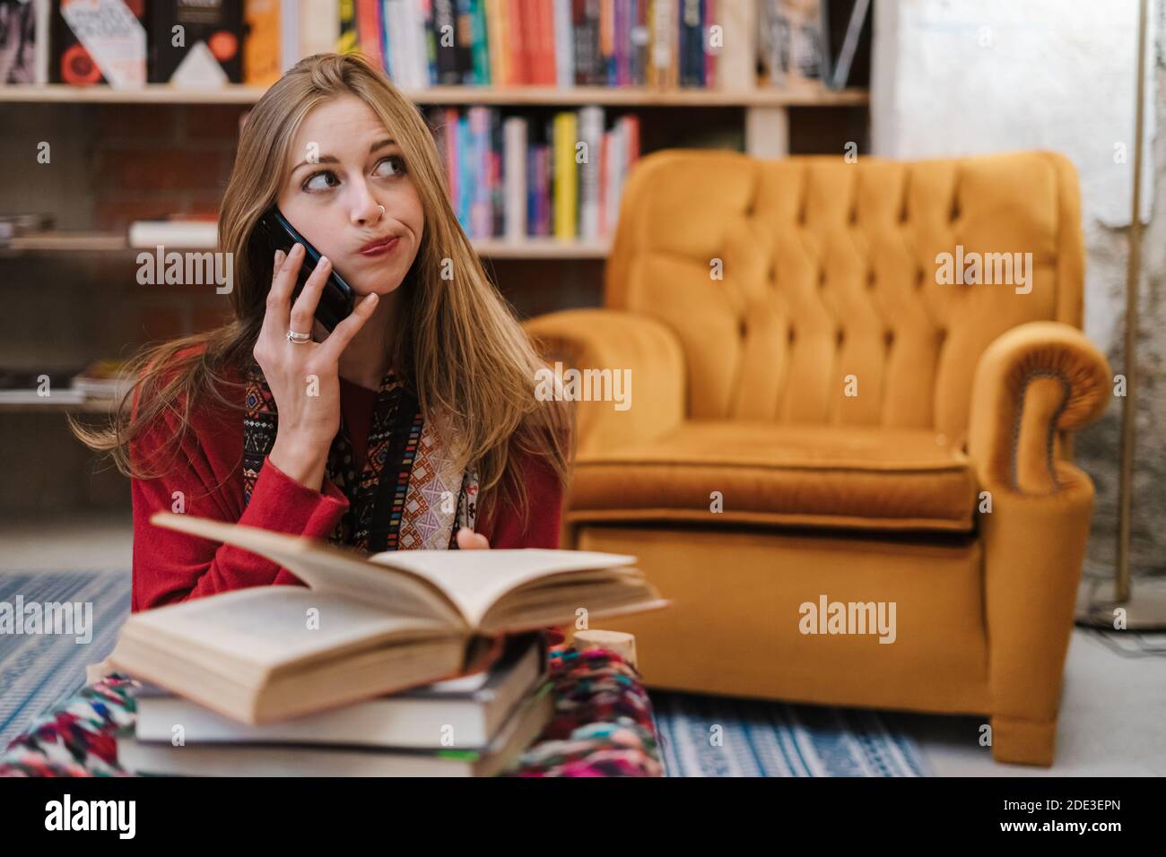 Blonde Frau, die einen Anruf in der Warteschlange in einer Buchhandlung entgegennimmt. Stockfoto