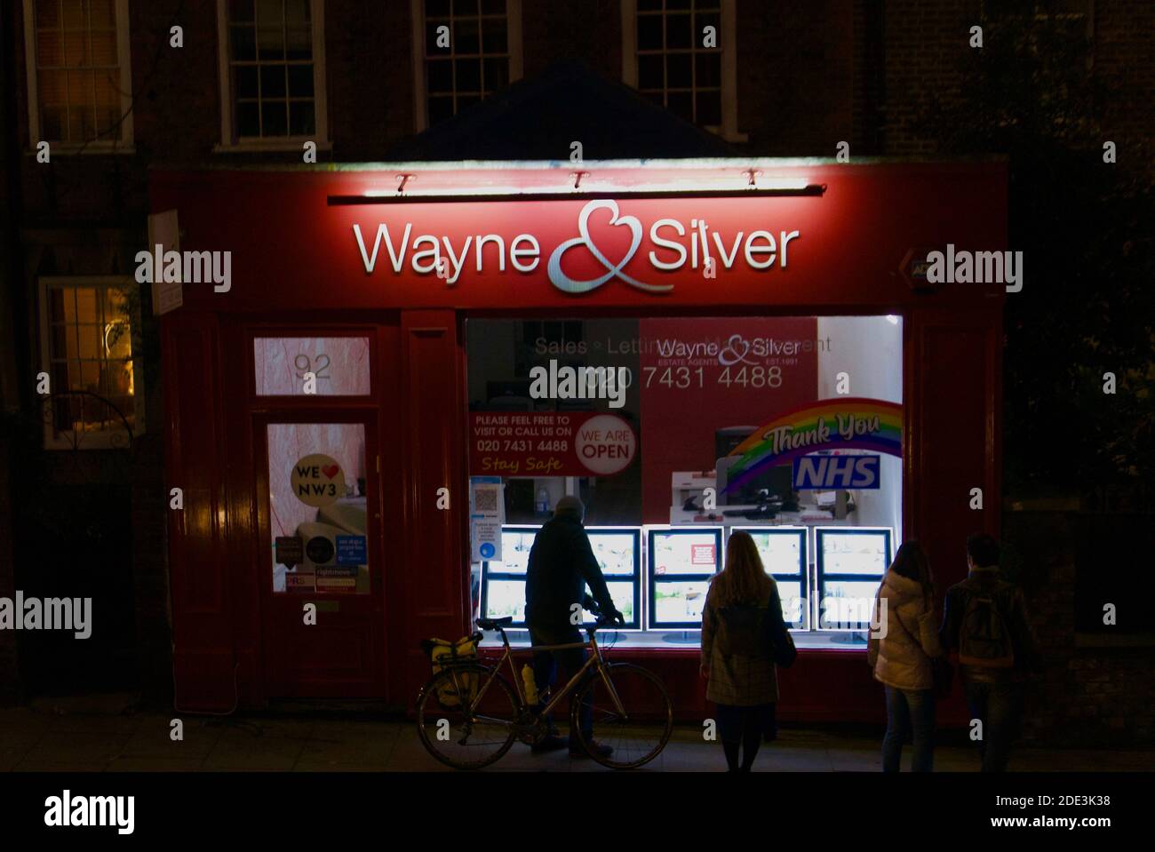 Menschen suchen im Fenster eines Immobilienmaklern (Wayne und Silver) Browsing Häuser zum Verkauf & Wohnungen zu vermieten / mieten in Hampstead & Highgate. Stockfoto