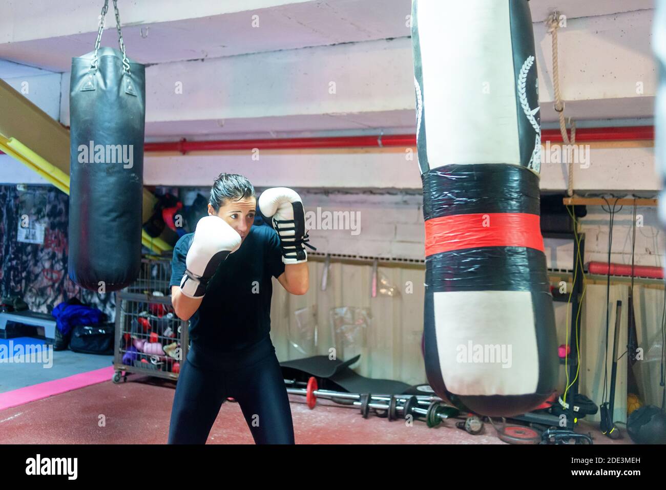 Boxerin trifft einen riesigen Boxsack in einem Boxstudio. Stockfoto