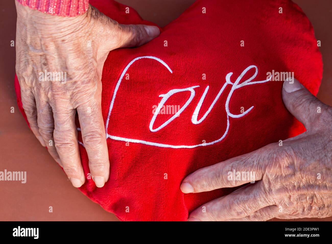 Von oben der Ernte anonyme romantische ältere Paar hält rot Inschrift Herz mit Liebe Stockfoto