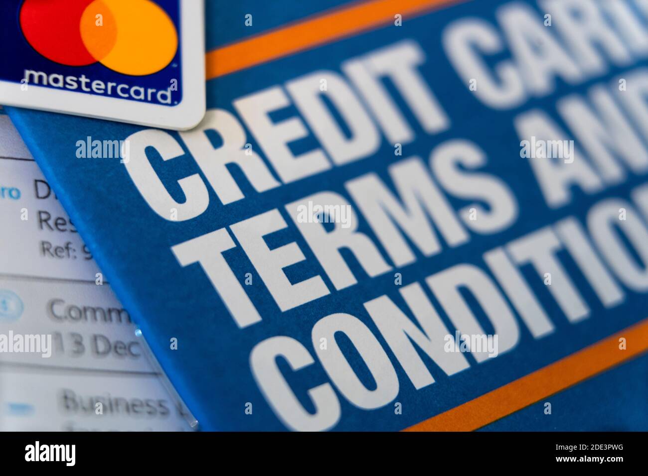 Eine Broschüre mit dem Titel Kreditkarten-Bedingungen mit einer überlappenden Kreditkarte mit dem Mastercard-Logo. Kreditkarten, Schulden, Schulden. VEREINIGTES KÖNIGREICH Stockfoto