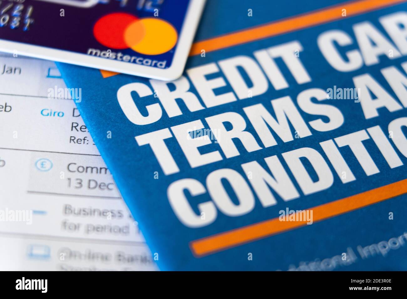 Eine Broschüre mit dem Titel Kreditkarten-Bedingungen mit einer überlappenden Kreditkarte mit dem Mastercard-Logo. Kreditkarten, Schulden, Schulden. VEREINIGTES KÖNIGREICH Stockfoto