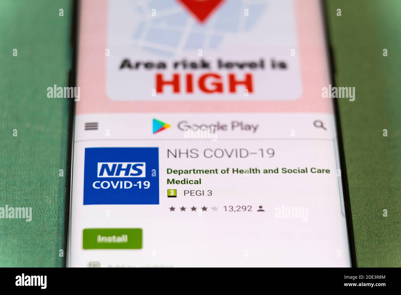 Ein Smartphone zeigt den Google Play-Bildschirm für die NHS covid-19 App für die Verwendung in Großbritannien und zeigt die Region Risiko ist hoch, Großbritannien Stockfoto