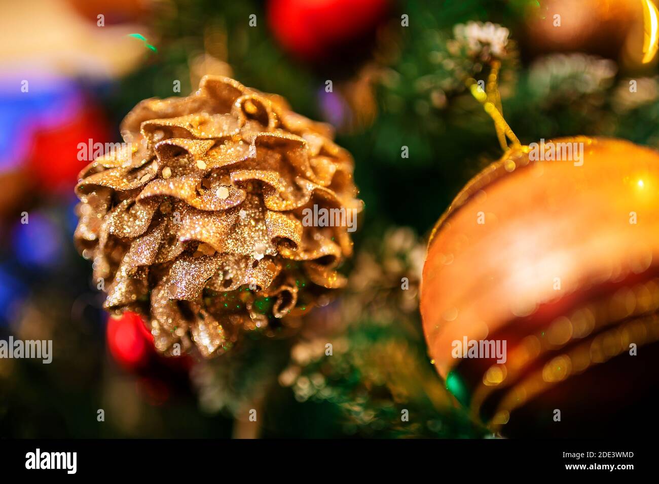 Thema „Neujahr“. Nahaufnahme. Ein Weihnachtsspielzeug in Form eines Kiefernkegels, unscharf geschossen, hängt an einem künstlichen Weihnachtsbaum Stockfoto