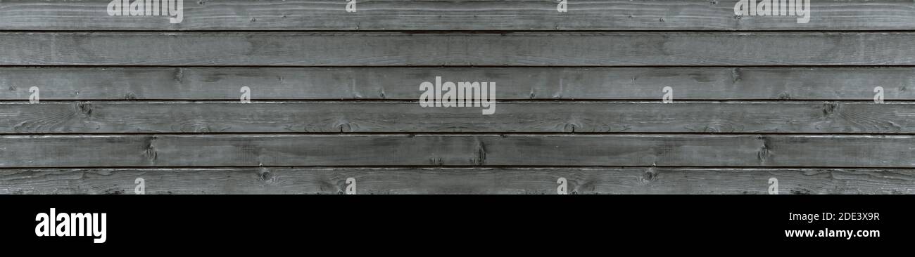 Die Textur des alten grauen Holzes, der Hintergrund der Bretter, das Panorama des alten ausgebrannten Holzhauses. Stockfoto
