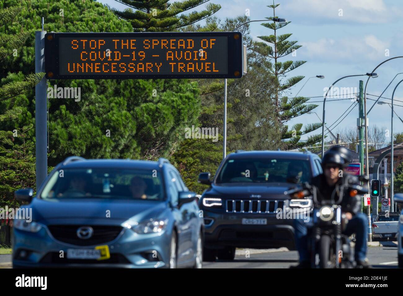 Verkehr auf dem General Holmes Drive in Kyeemagh an der Botany Bay in der Nähe des Flughafens Sydney in Sydney, Australien, mit einem öffentlichen Hinweisschild, das vor den Risiken unnötiger Reisen während der COVID-19 Coronavirus-Pandemie warnt. Stockfoto