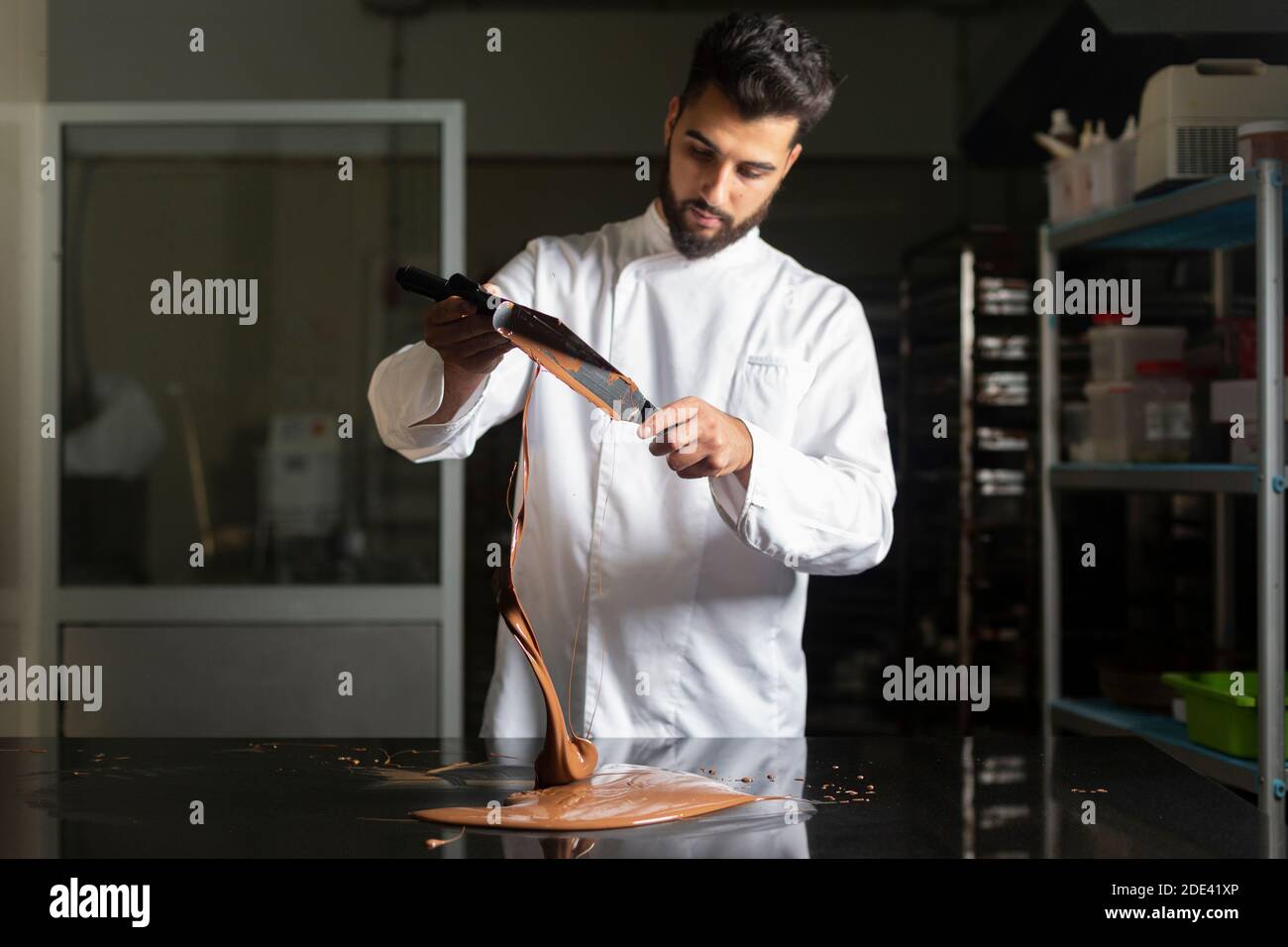Der Konditor arbeitet an der Temperierung von Schokolade auf dem Marmortisch Stockfoto