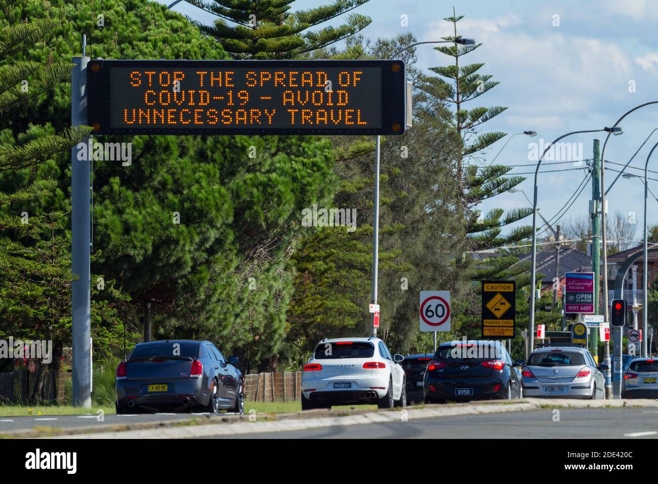 Verkehr auf dem General Holmes Drive in Kyeemagh an der Botany Bay in der Nähe des Flughafens Sydney in Sydney, Australien, mit einem öffentlichen Hinweisschild, das vor den Risiken unnötiger Reisen während der COVID-19 Coronavirus-Pandemie warnt. Stockfoto