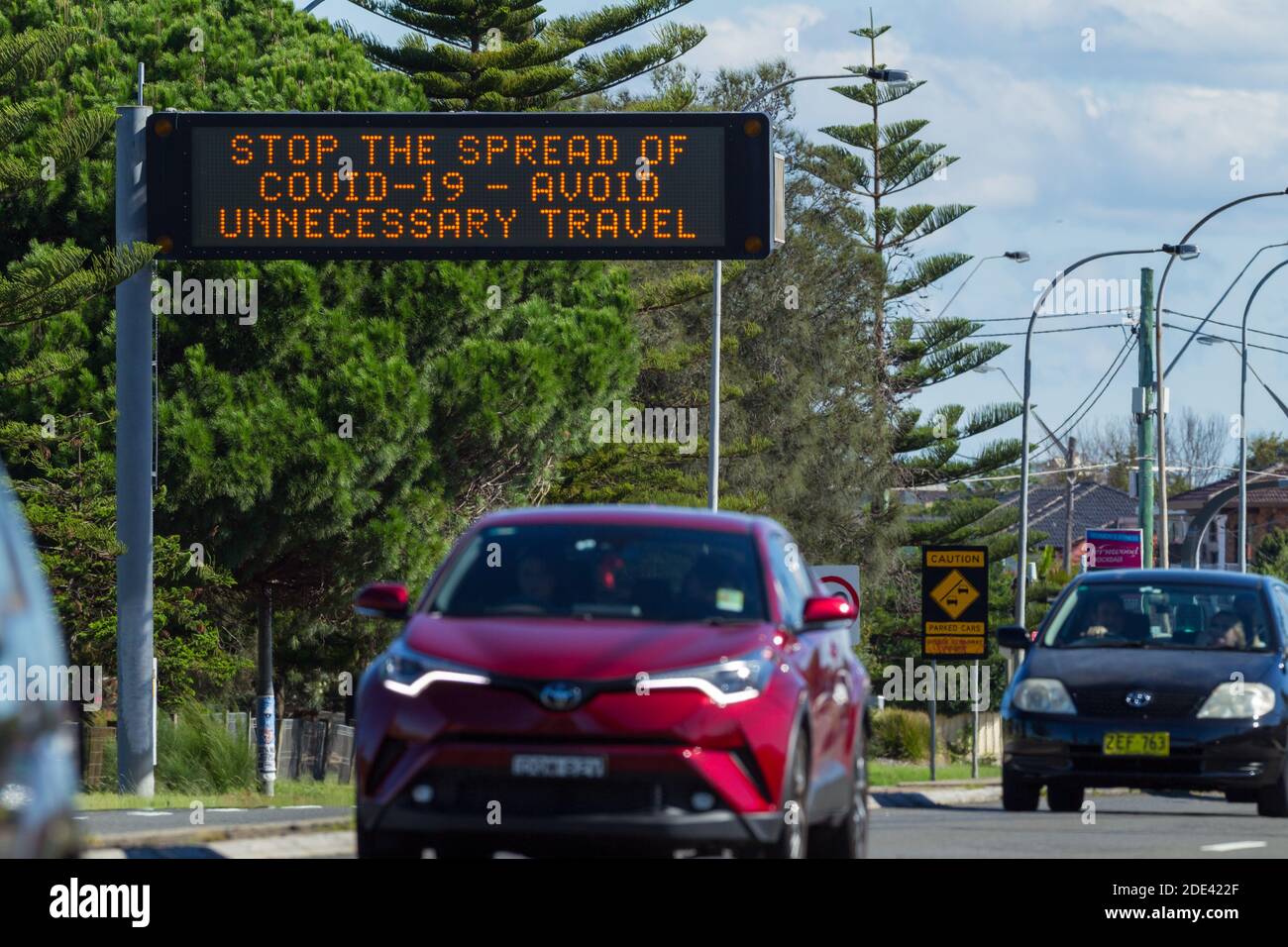 Verkehr auf dem General Holmes Drive in Kyeemagh an der Botany Bay in der Nähe des Flughafens Sydney in Sydney, Australien, mit einem öffentlichen Hinweisschild, das vor den Risiken unnötiger Reisen während der COVID-19 Coronavirus-Pandemie warnt. Stockfoto