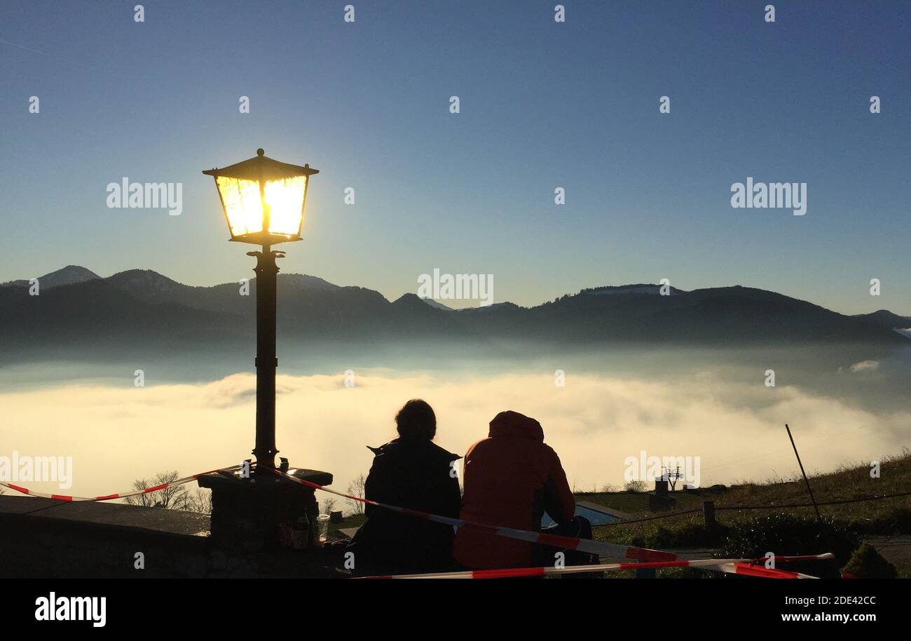 Schliersee, Deutschland. November 2020. Wanderer sitzen auf der Schliersbergalm, 1061 Meter über dem Schliersee, und genießen die Sonne, während eine dicke Wolkenschicht über dem See hängt. Quelle: Sabine Dobel/dpa/Alamy Live News Stockfoto