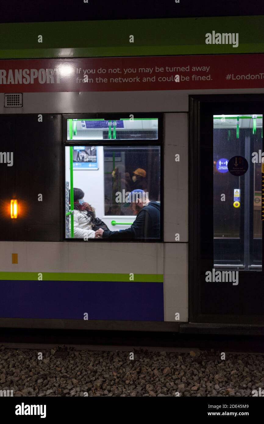 Passagiere entlarvt auf einer Croydon Tramlink Straßenbahn während der covid 19 Pandemie, Coronavirus Pandemie eine mit einer Gesichtsmaske eine ohne. Stockfoto