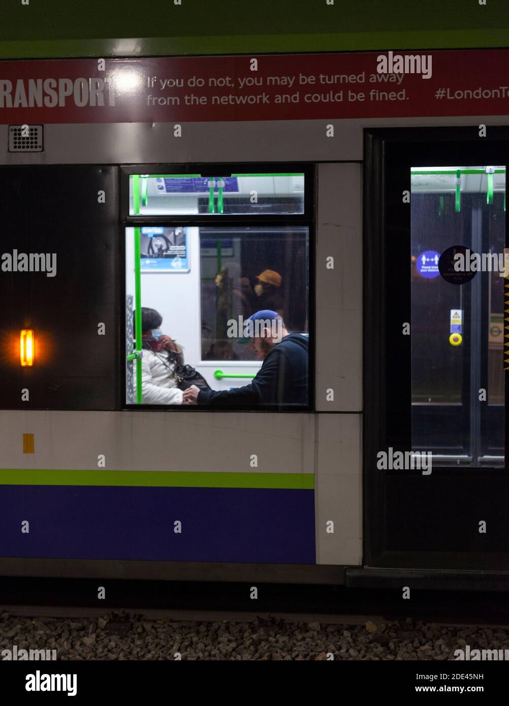 Passagiere entlarvt auf einer Croydon Tramlink Straßenbahn während der covid 19 Pandemie, Coronavirus Pandemie eine mit einer Gesichtsmaske eine ohne. Stockfoto