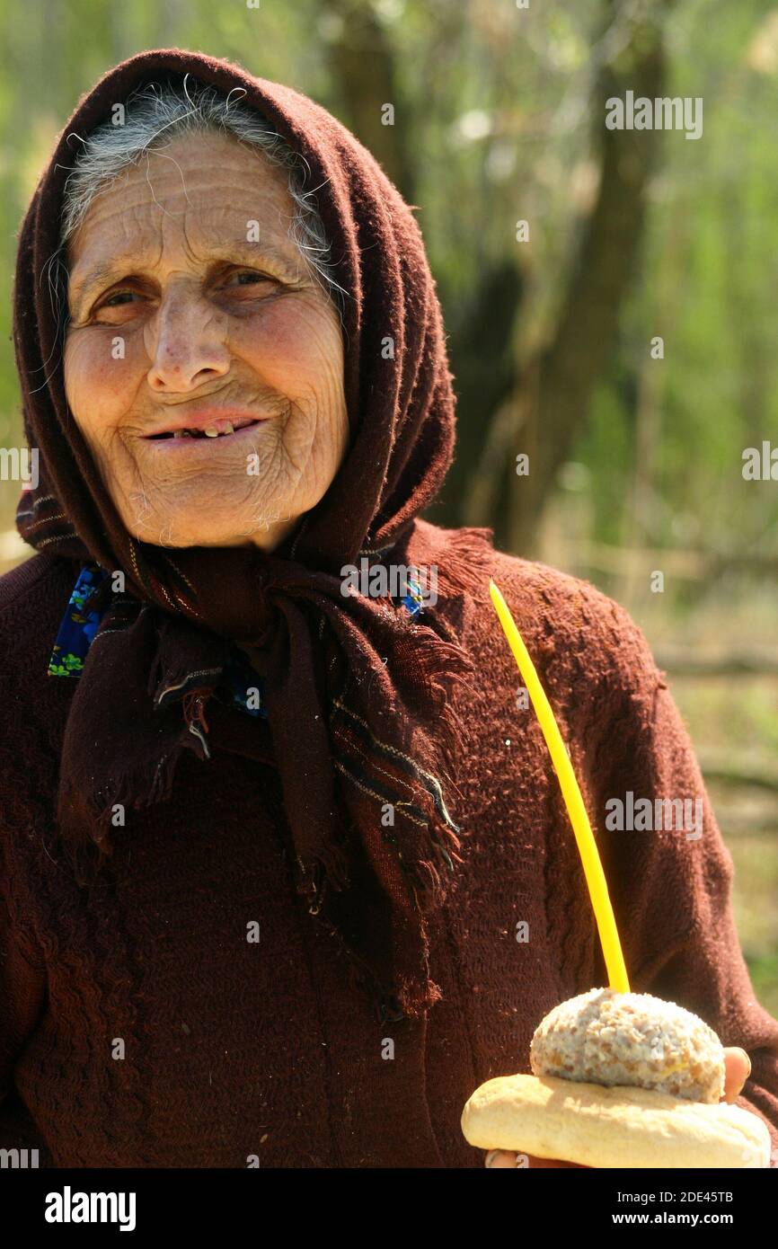 Ältere Frau mit Oliva, Brot und einer Kerze Almosen für die Seele eines Toten gegeben. Religiöser Brauch in Rumänien. Stockfoto