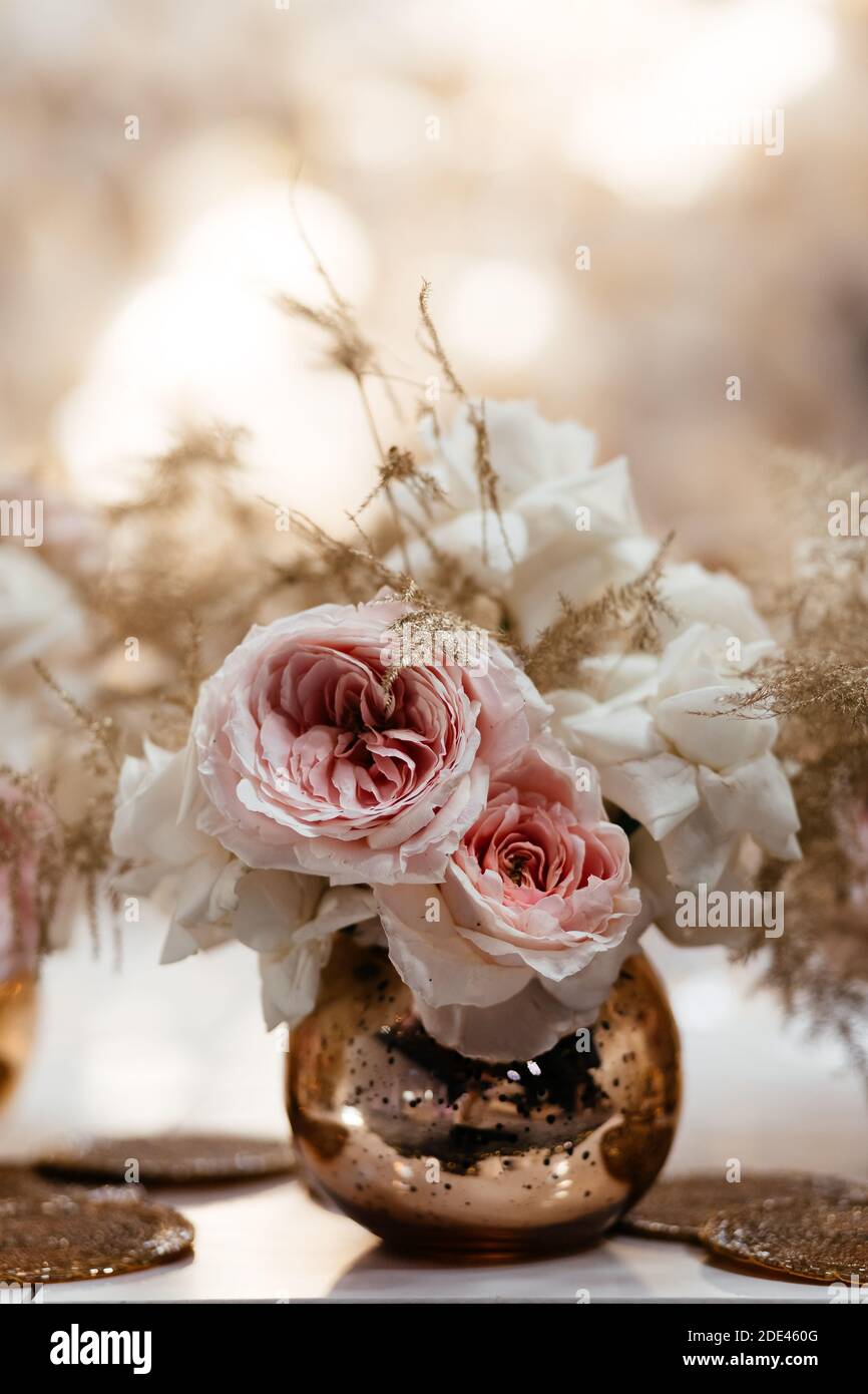 Weiße und rosa Rosen in der kleinen goldenen Vase mit dem Platz für Ihren Text. Dekoration im Hochzeitsrestaurant. Hochzeitsbankett. Stockfoto