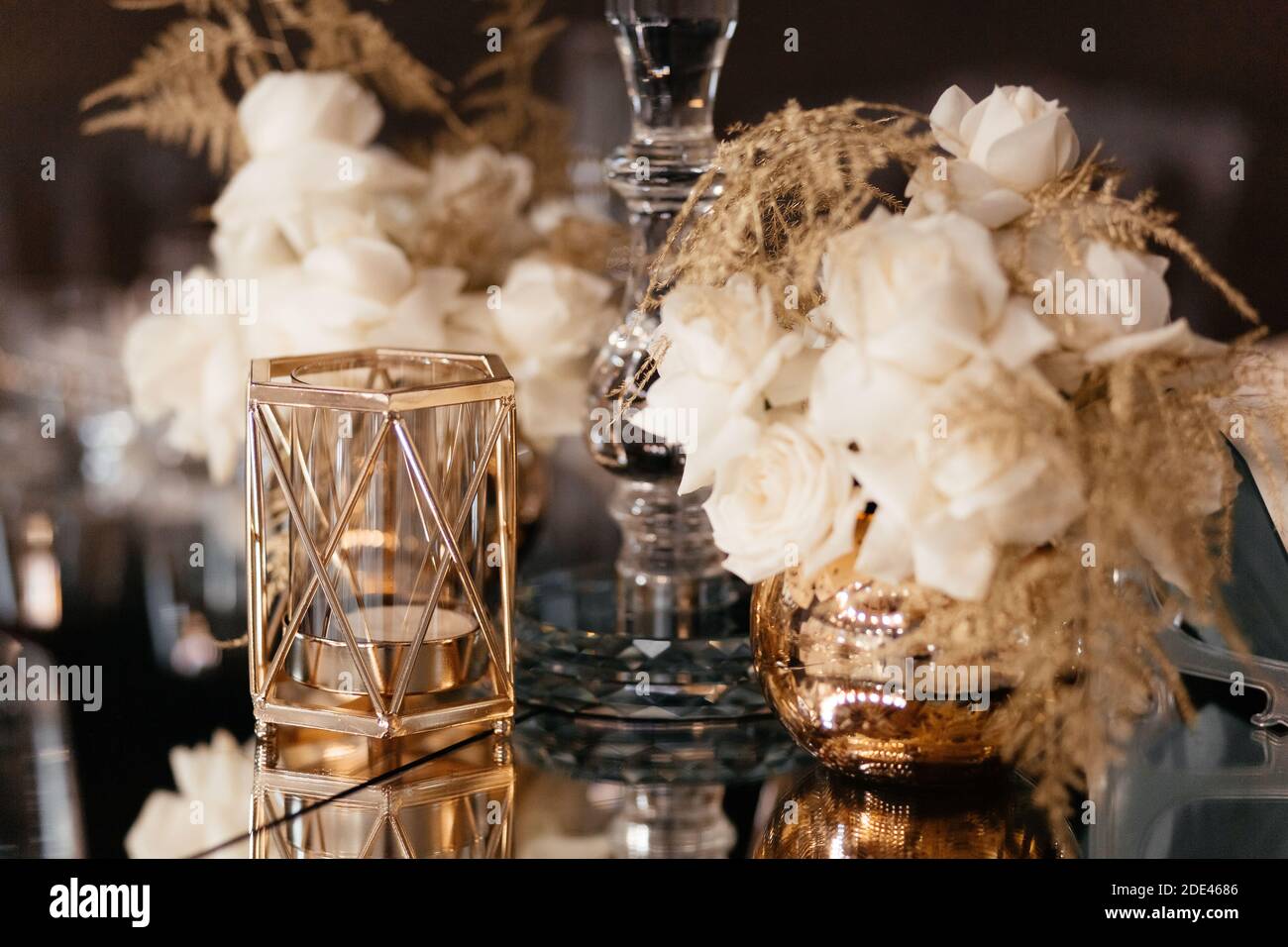 Goldener Kerzenständer und kleiner Blumenstrauß in der Vase. Dekoration im Hochzeitsrestaurant. Hochzeitsbankett. Stockfoto