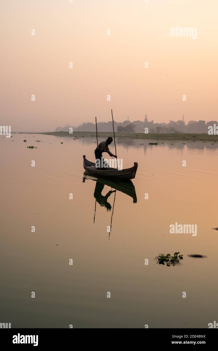 Fischer steht mit Boot auf dem Taung Tha man See zum Sonnenaufgang, Reflexion im Wasser, Thaung Tha man See, Mandalay, Myanmar Stockfoto