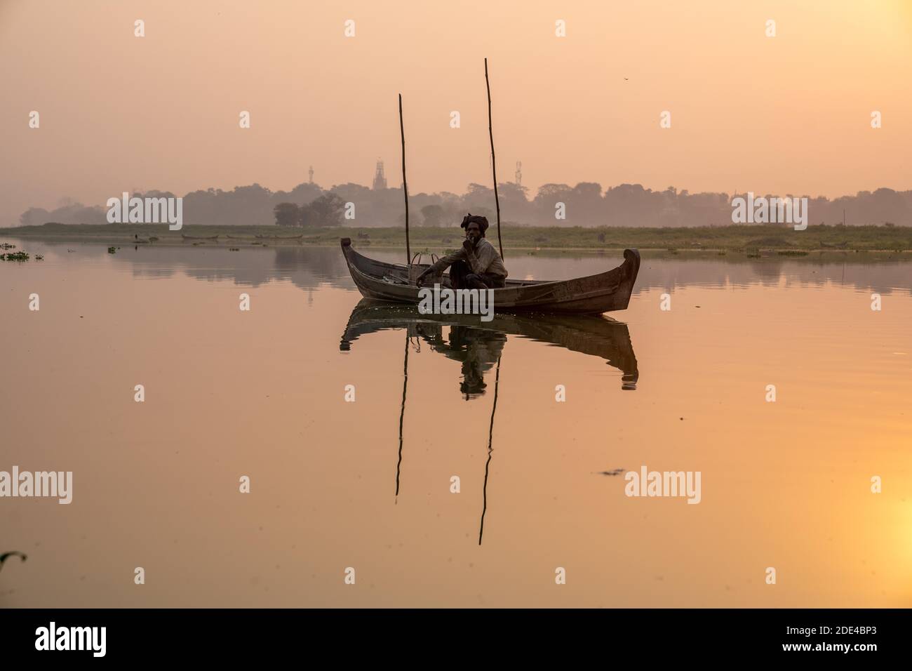Fischer sitzen mit Boot auf Taung Tha man Lake bei Sonnenaufgang, Reflexion im Wasser, Thaung Tha man Lake, Mandalay, Myanmar Stockfoto