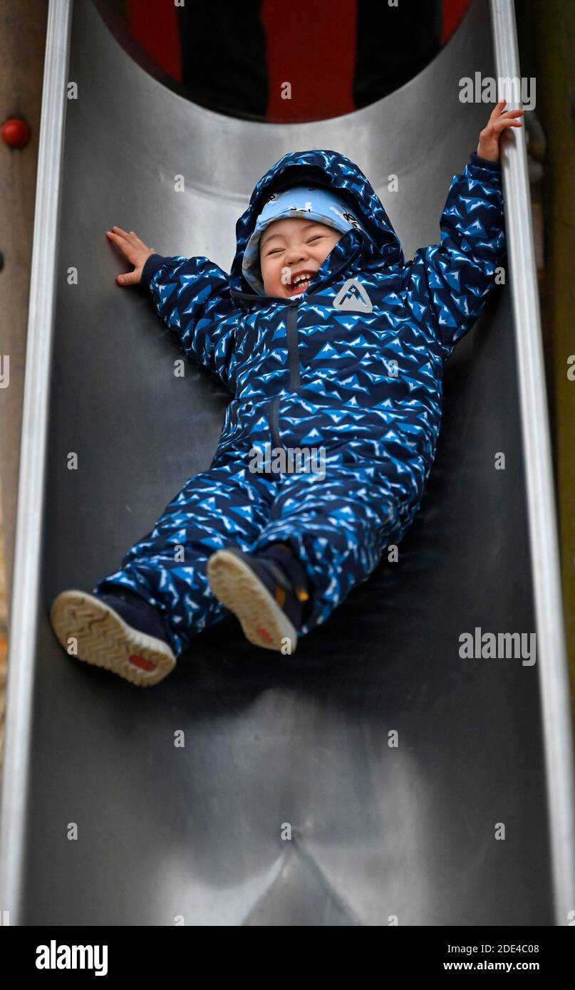 Kleinkind, Junge, 15 Monate, multiethnisch, auf Kinderrutsche, lachend, Stuttgart, Baden-Württemberg, Deutschland Stockfoto