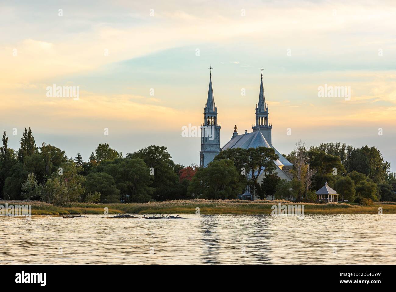 Die Kirche von Saint-Roch-des-Aulnaies, Quebec, Kanada, bei Sonnenuntergang mit dem St. Lawrence Fluss im Vordergrund. Stockfoto