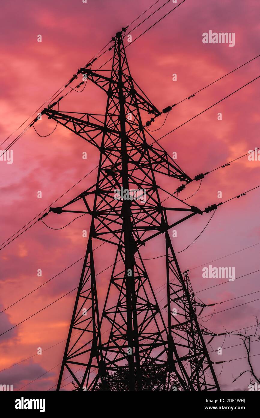 Elektrischer Turm (Strompylon) auf hellem Donner Sonnenuntergang Himmel. Hochspannung. Hohe Struktur. Stockfoto