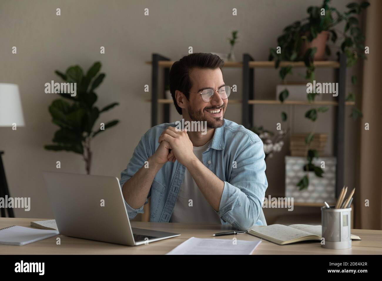 Lächelnder junger Mann Traum abgelenkt von Computer-Arbeit Stockfoto