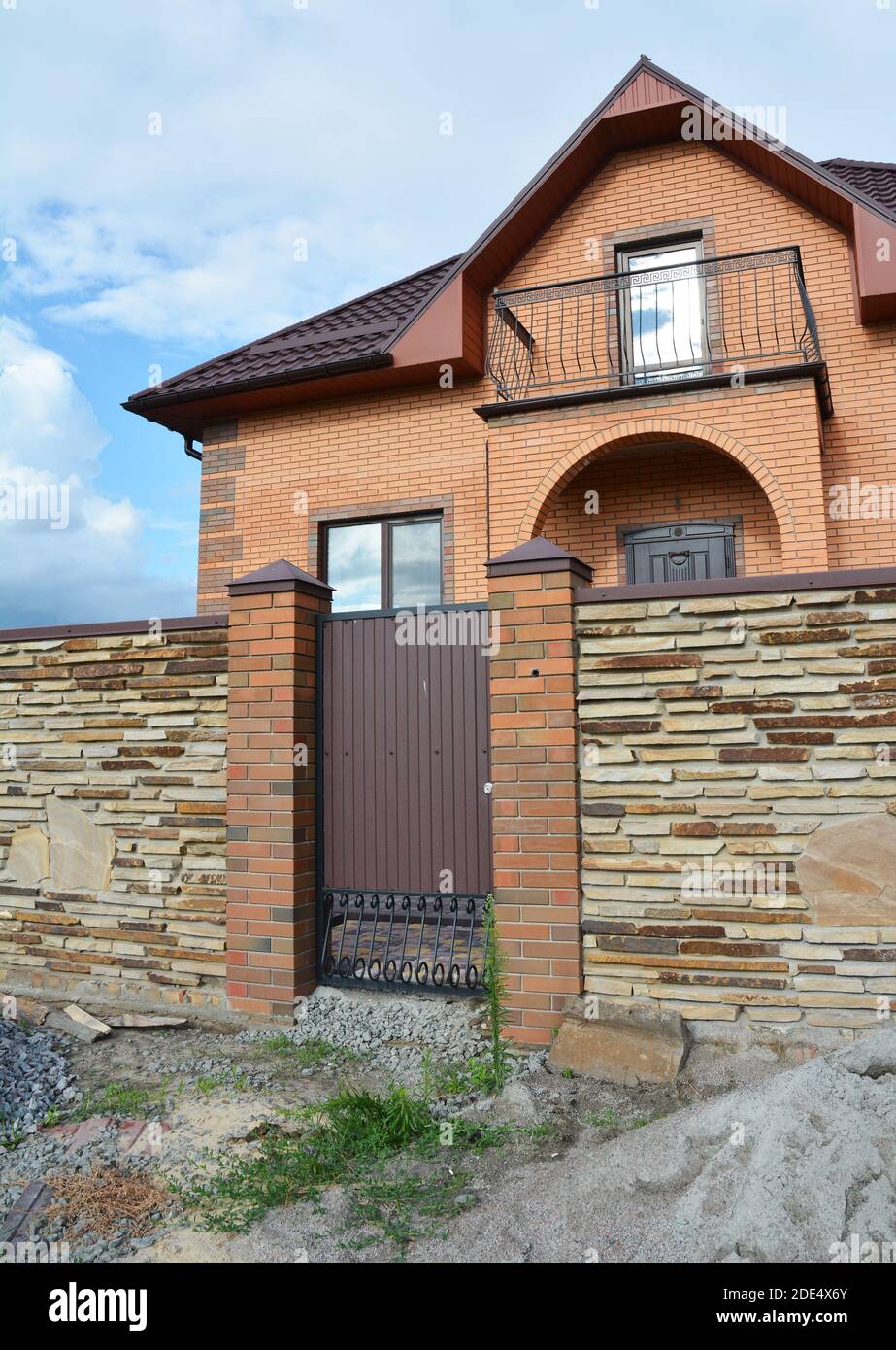 Modernes Backsteinhaus im Bau mit Steinzaun und Metall Eingangstür. Stockfoto