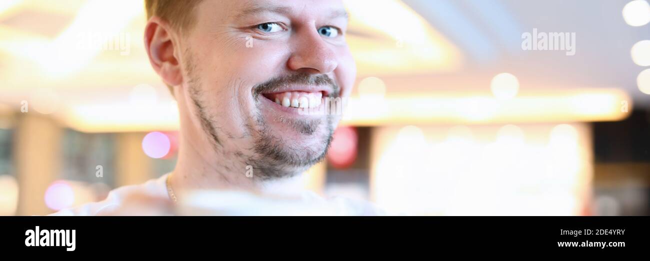 Lächelnder Mann, der im Café mit einer großen Tasse Kaffee sitzt Stockfoto