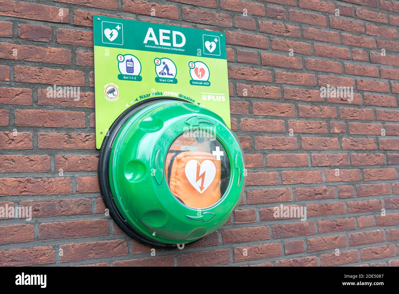 Automatisierter externer Defibrillator (AED) an einer Ziegelwand. Tragbares elektronisches erste-Hilfe-Gerät zur Wiederherstellung des Herzrhythmus. Stockfoto