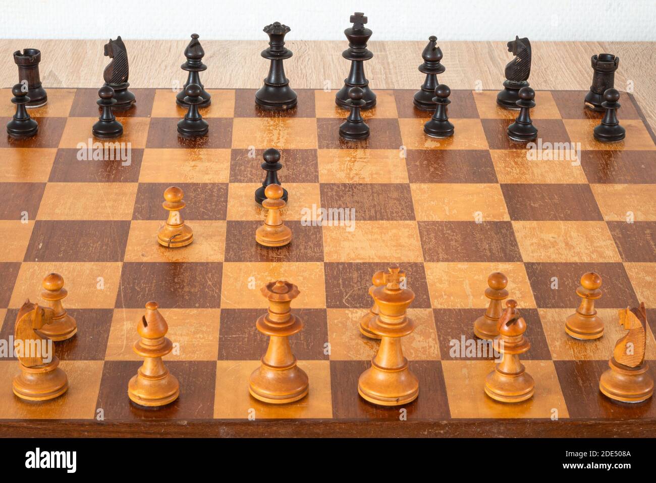 Stücke auf einem Schachbrett. Die Anordnung der Stücke stammt von einer Öffnung, die als Queen's Gambit bekannt ist. Stockfoto