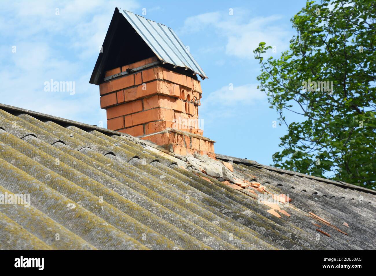 Haus Asbest Dach mit einem alten Ziegel beschädigten Kamin. Stockfoto