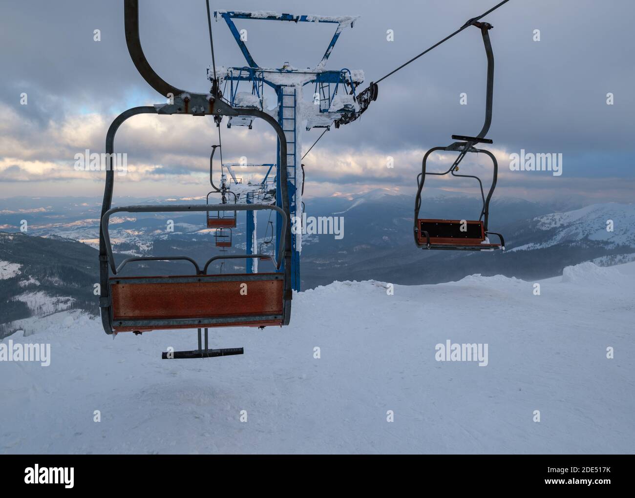 Alpine Resortr Skilift mit Sitzen über den Sonnenuntergang Ski-Pisten in den Bergen bei extrem windigem Wetter Stockfoto