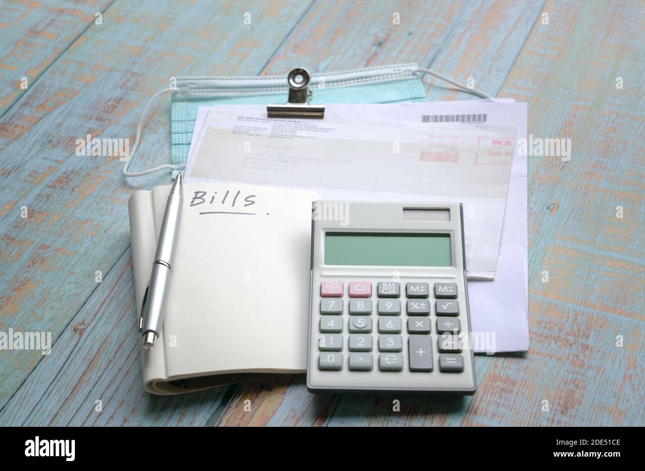 Rechnungen, Taschenrechner, Notizblock und Gesichtsmaske auf Holztisch. Krise während des Pandemiekonzepts. Stockfoto