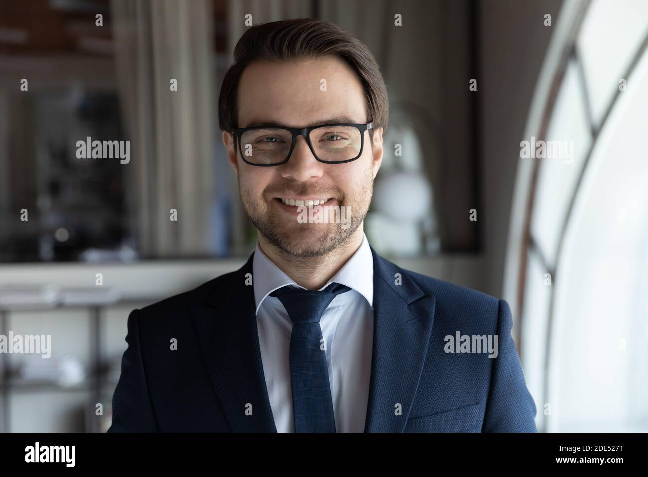 Motivierter junger Manager im Anzug mit Blick auf die Kamera im Büro Stockfoto