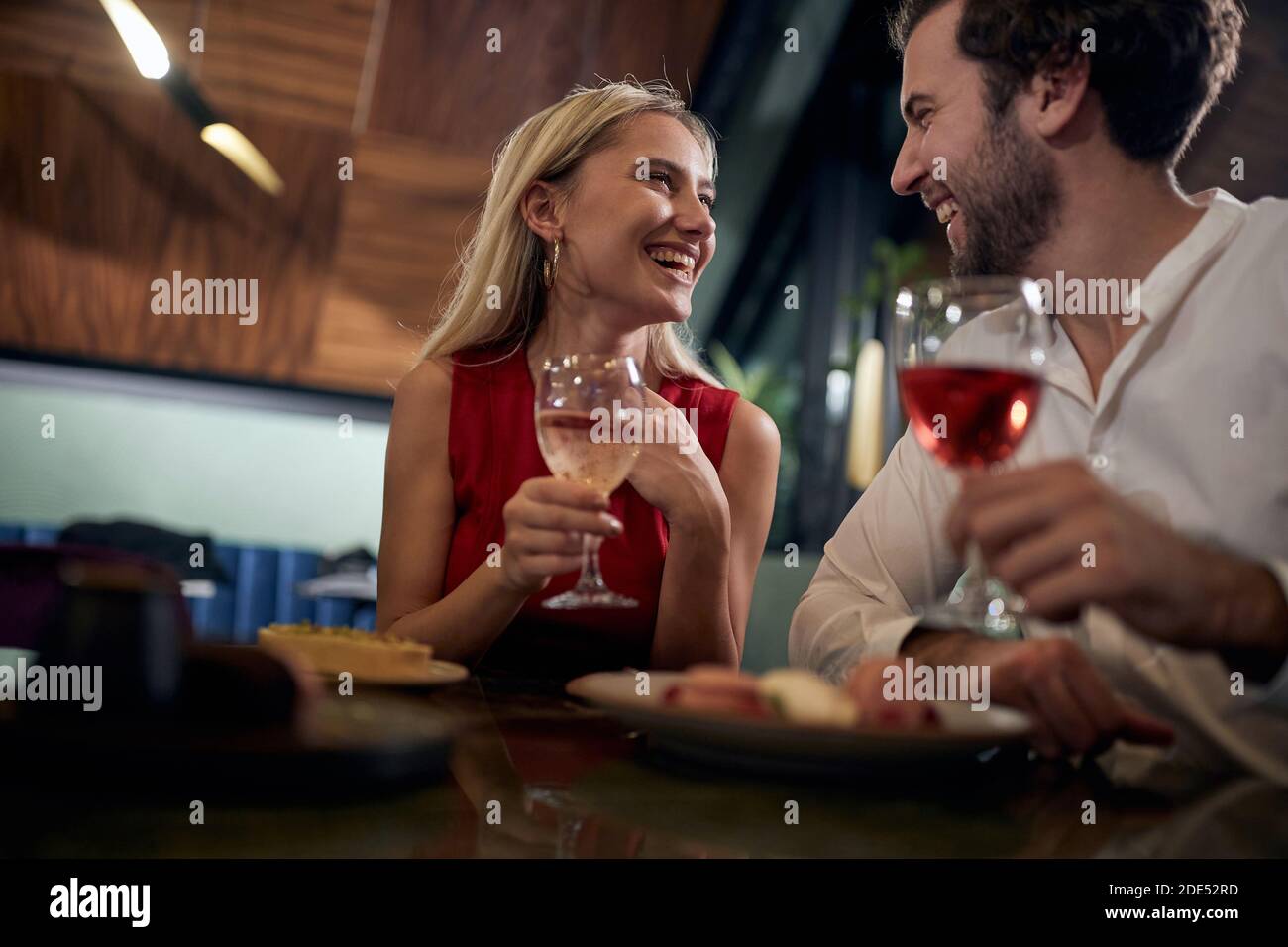 Junges Paar, das sich anschaut, lächelt, lacht, ein romantisches Abendessen in einem Restaurant hat, das neue Jahr feiert. Stockfoto