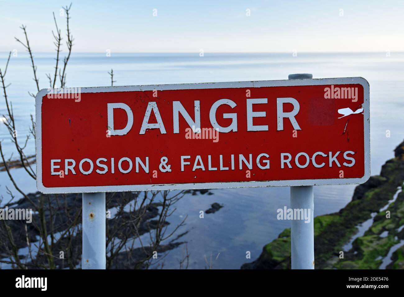 Rote und weiße Zeichen Gefahr Erosion und Falling Rocks an der Klippe Kante in St Andrews, Schottland genommen. Meer und Felsen im Hintergrund unten. Stockfoto