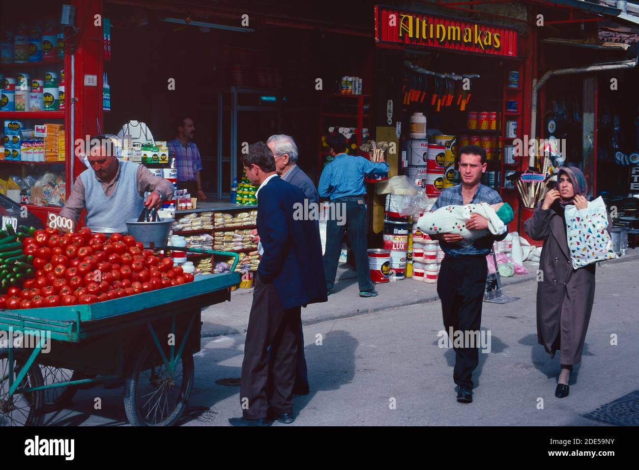 Straßenszene mit Marktstand, General Store & traditionelles türkisches Paar mit Baby Walking in den Straßen von Bursa Türkei Stockfoto