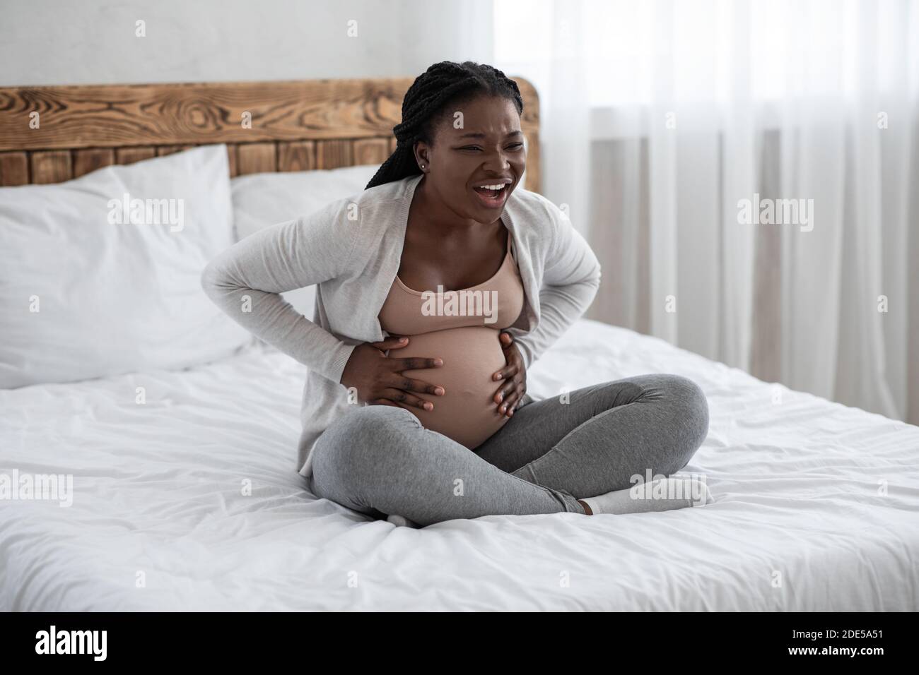 Schwangere schwarze Dame mit Wehen Kontraktionen zu Hause, leiden unter Bauchschmerzen Stockfoto