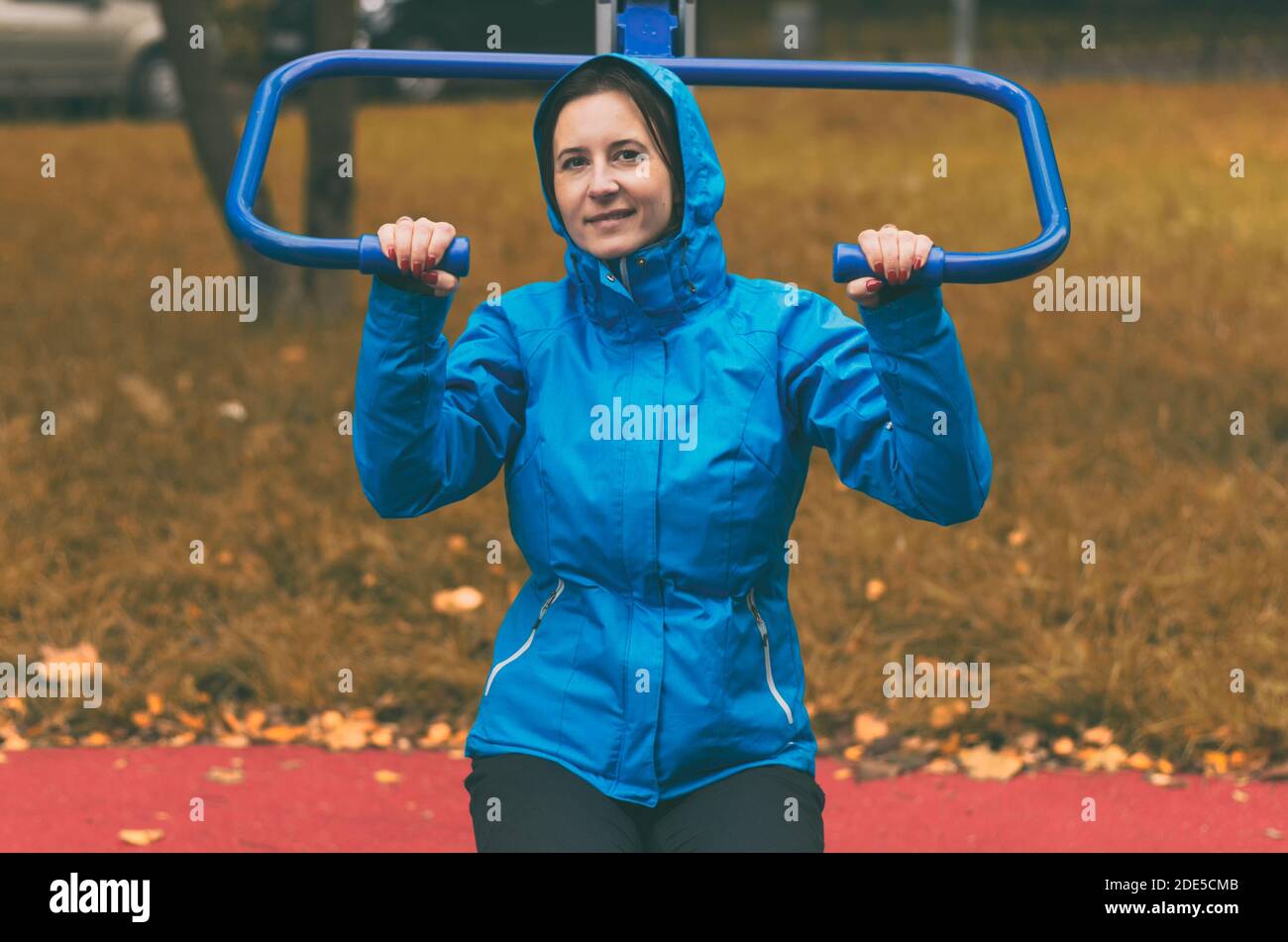 Junge Frau in einer Kapuzenjacke macht Sport Ein Simulator im indischen Sommer Stockfoto