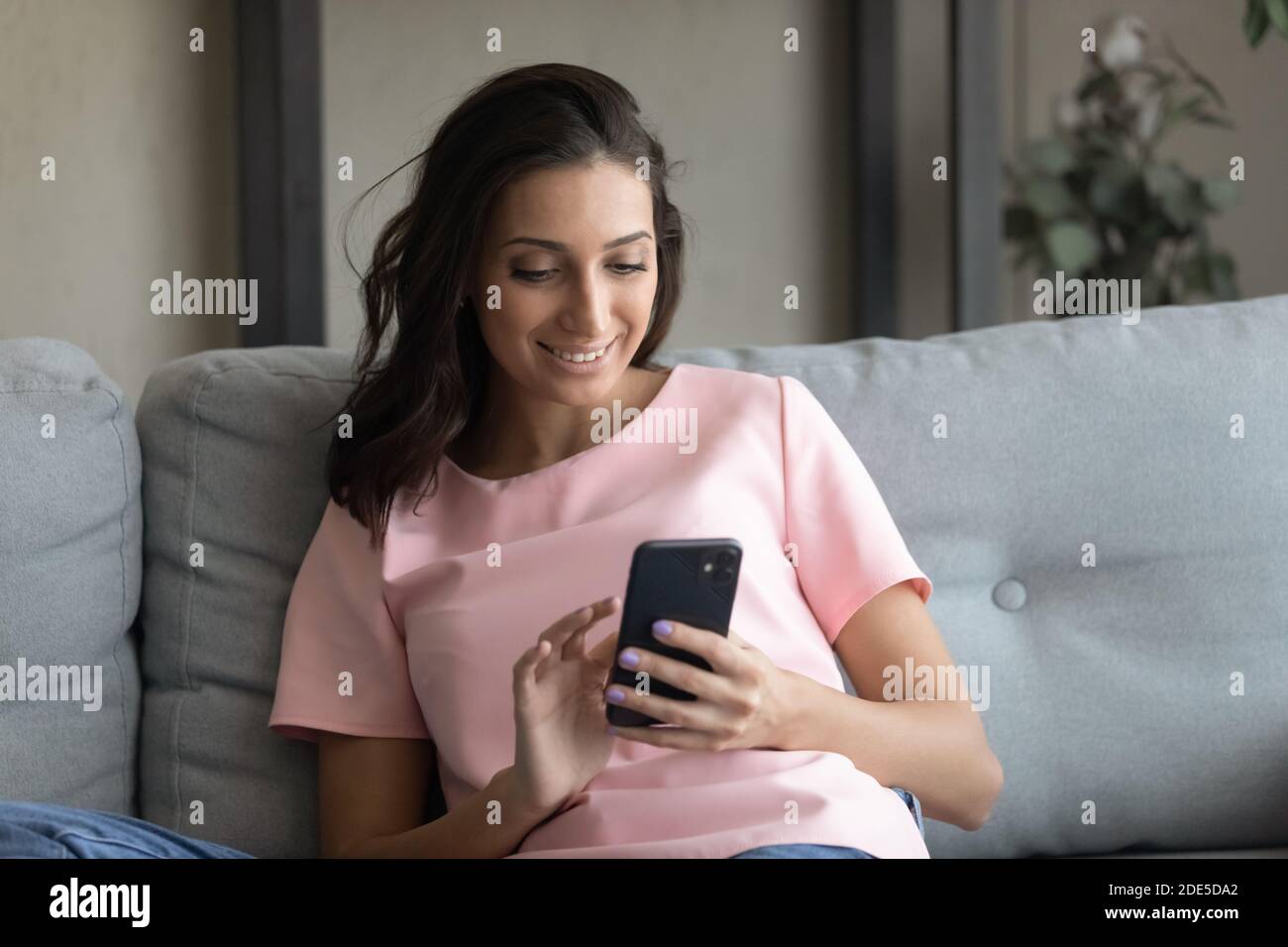 Glückliche junge gemischte Rennen Frau Lesen angenehme Nachricht auf dem Smartphone. Stockfoto